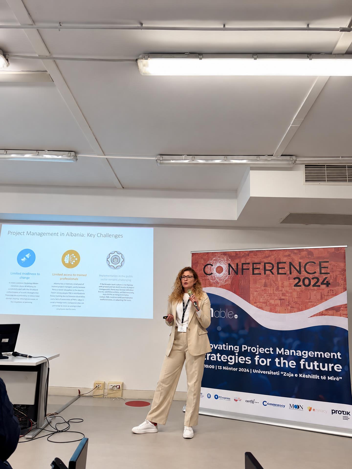 Olta Prifti speaking about project management at a conference in 2024
